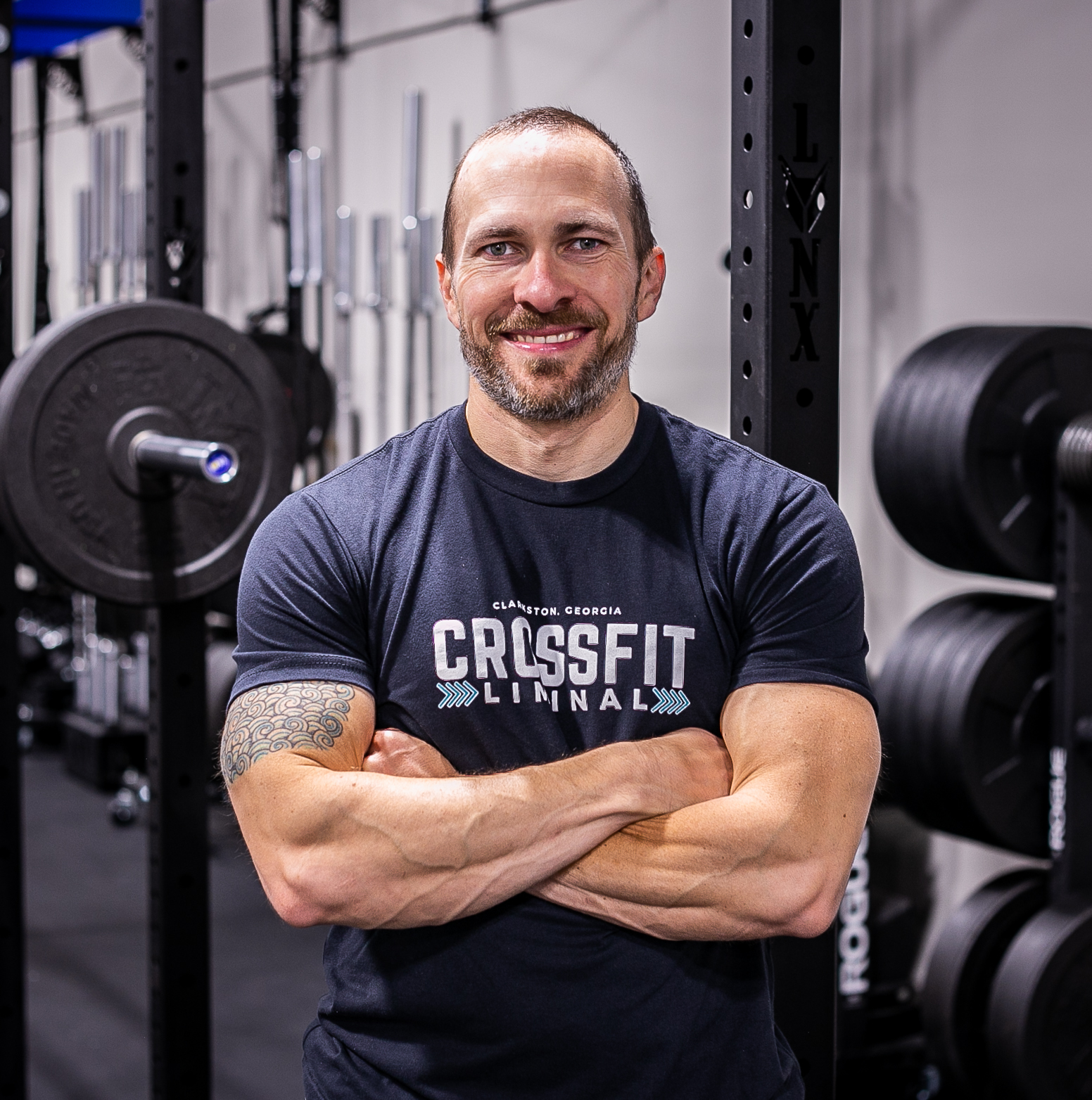 Liminal Health and Fitness founder smiling in gym and wearing CrossFit Liminal t-shirt.