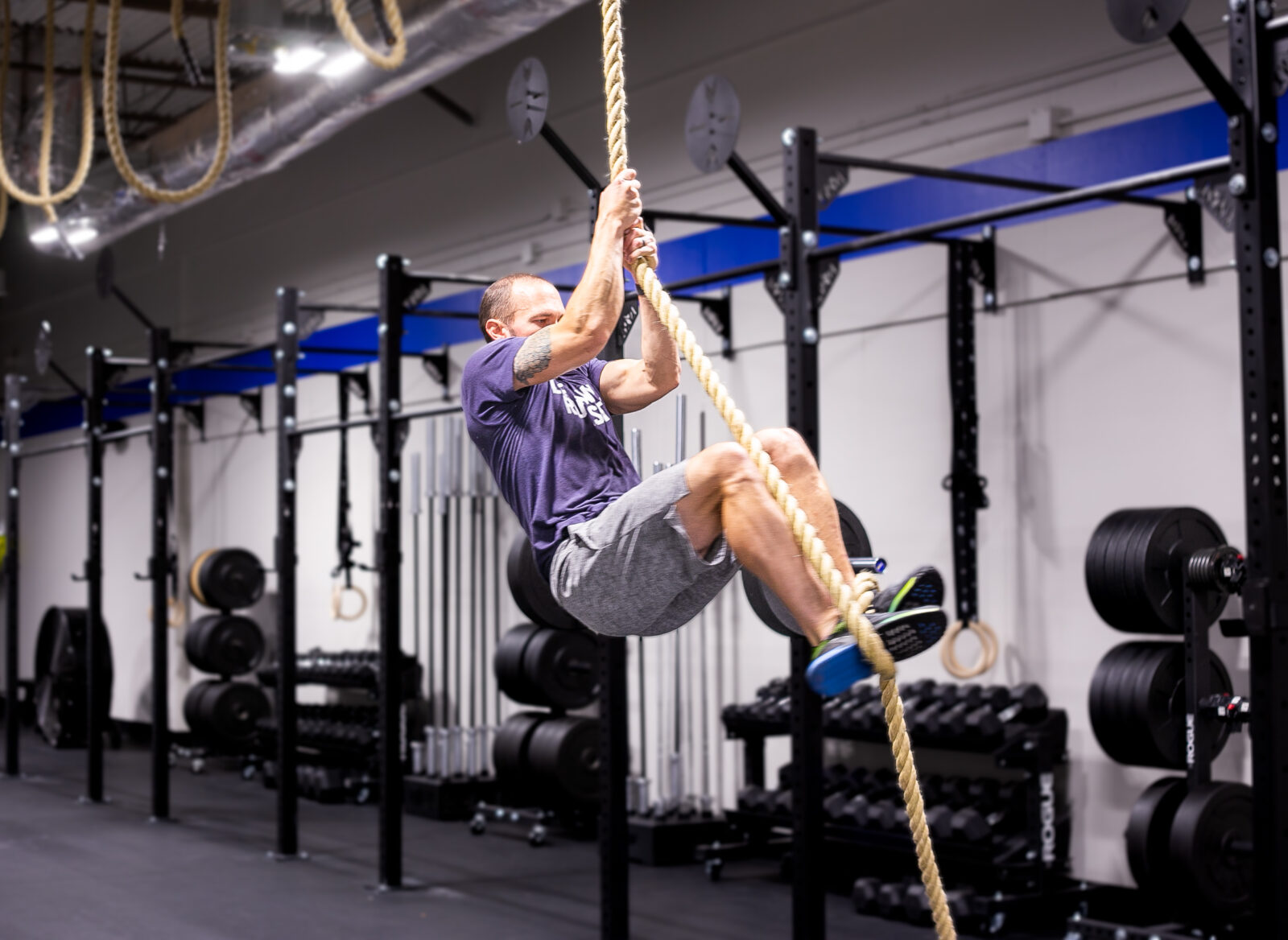 Man climbs rope in a fitness gym.