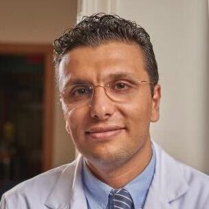 Member of board of directors, smiling and posing in white lab coat.