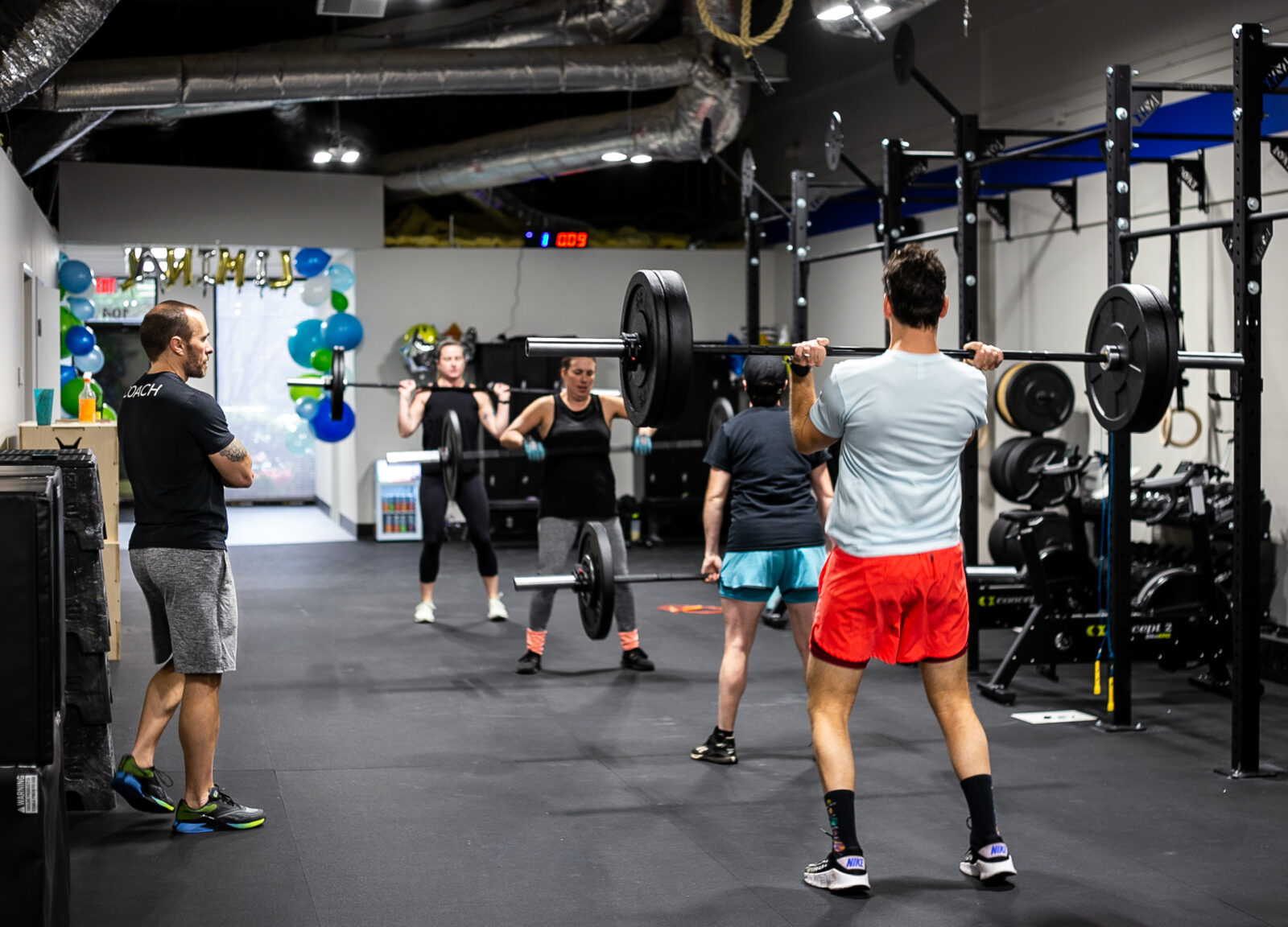 Several people lifting weights in a fitness gym.